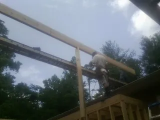Carpenter setting a ridge beam over a new addition frame — Ice Dam Removal by Roofing Brothers in Canisteo