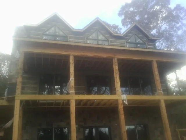 Dormers and porch framing on a large log home under construction — Roof Coating work by our crew in Canisteo