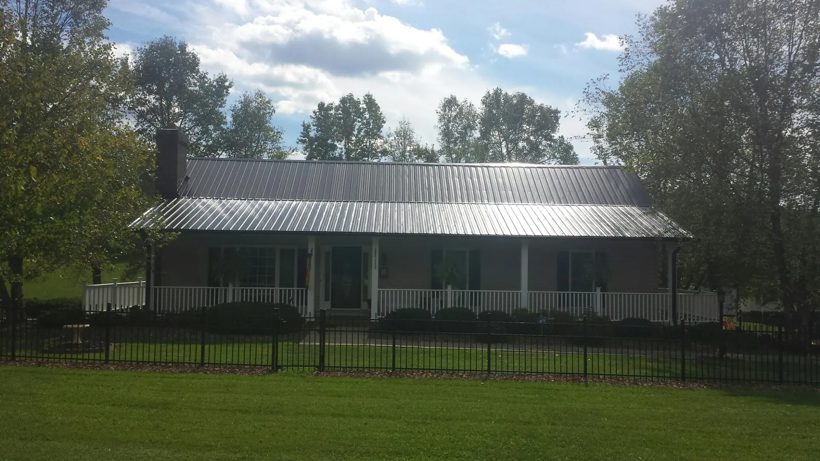 Gray metal roof on a brick ranch with a full width front porch — Gutter Guard Installation work by our crew in Canisteo