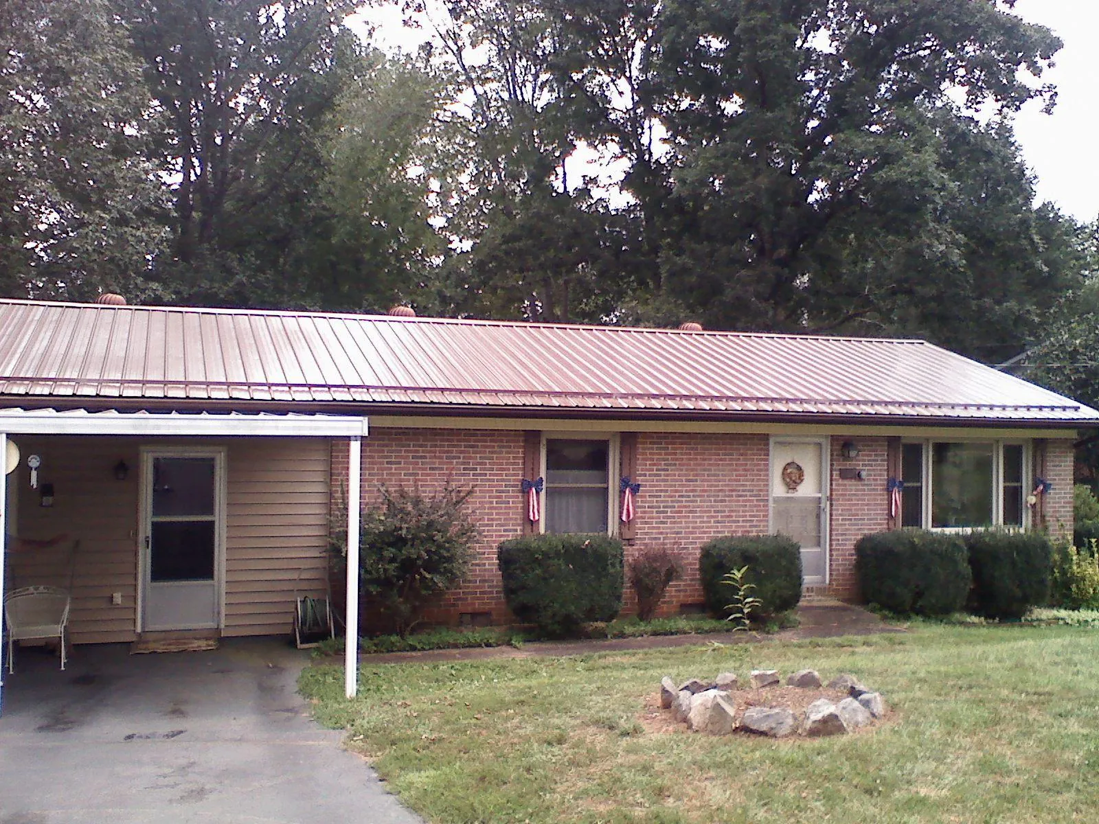 Bronze metal roof and carport on a brick ranch home — Roof Repair work by our crew in Canisteo