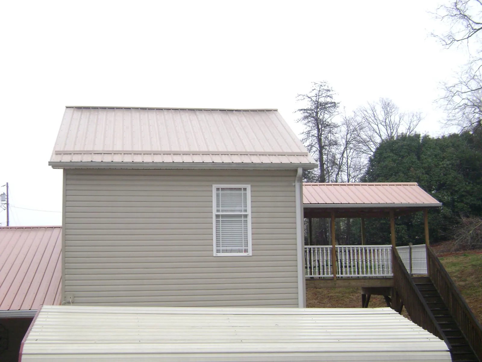 Tan metal roofs on a two story addition and attached porch in Canisteo