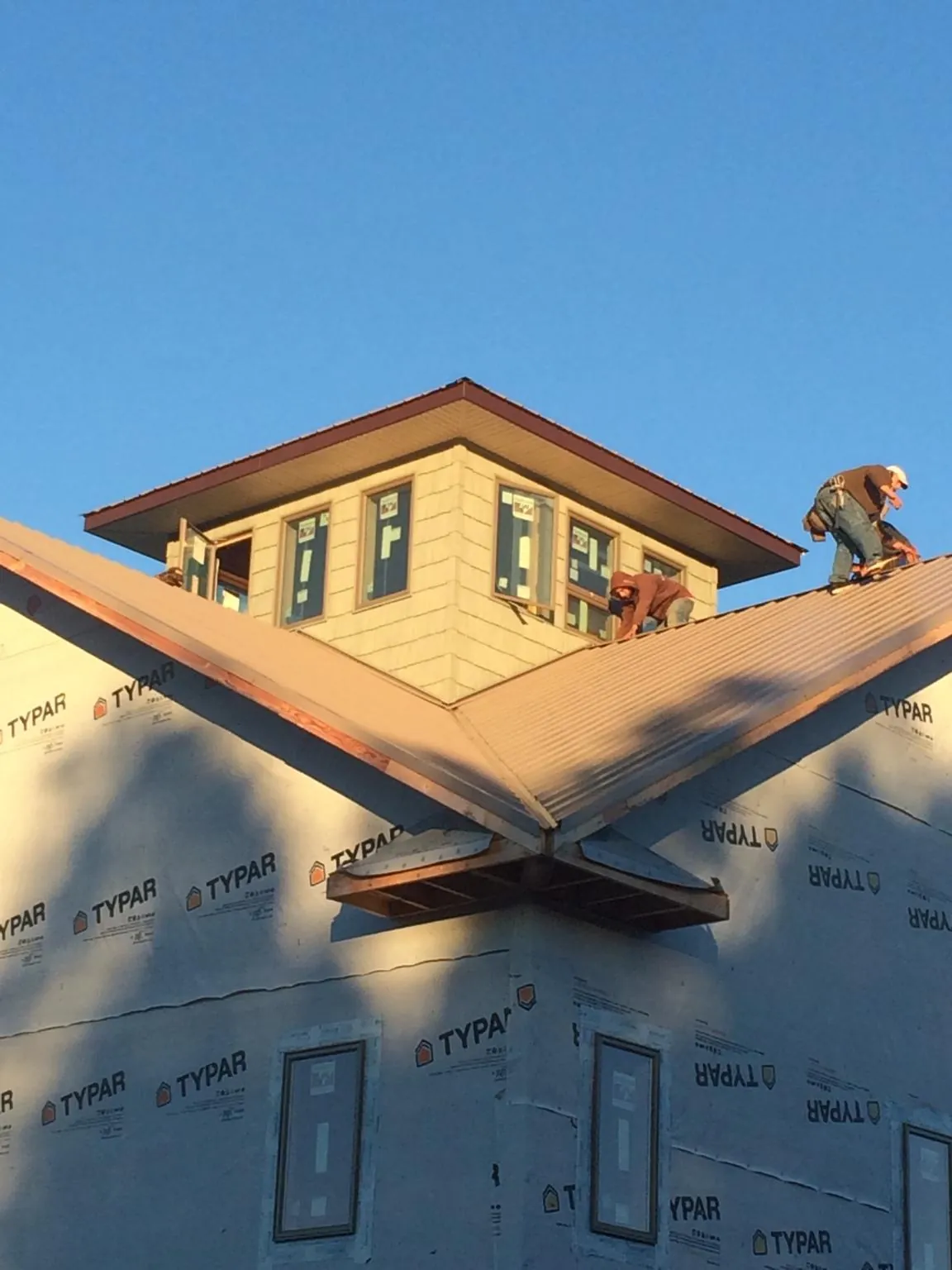 Roofers working around a rooftop cupola on a new metal roof at sunset — Roof Waterproofing in Canisteo by Roofing Brothers